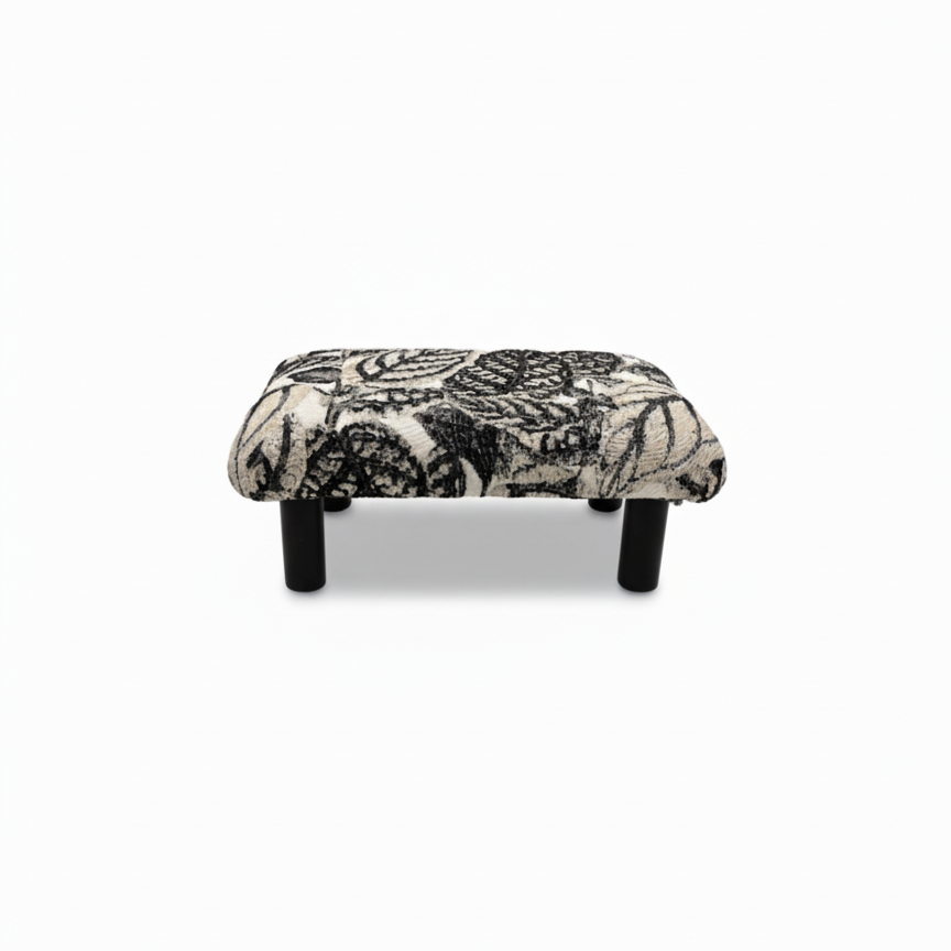 Handcrafted small footstool with black wood legs. It has a black and white leaf pattern fabric top.  It is displayed on a whitebackground. Made by Little Forest Studio
