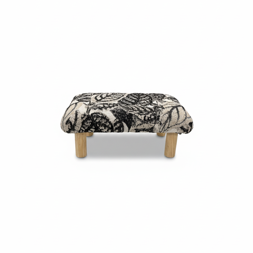 Handcrafted small footstool with natural color wood legs. It has a black and white leaf pattern fabric top.  It is displayed on a whitebackground. Made by Little Forest Studio