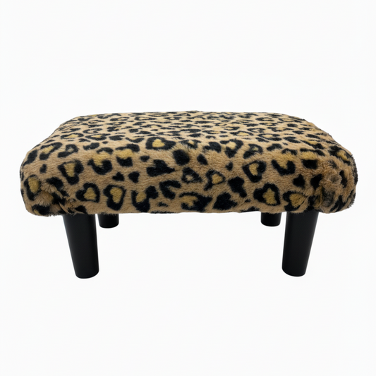 Handcrafted footstool with plush cheetah print faux fur top and black wood legs. On a white background. Made by Little Forest Studio.