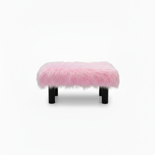 Handcrafted footstool with plush light pink shaggy faux fur top. It has wooden black legs. On a white background. Made by Little Forest Studio