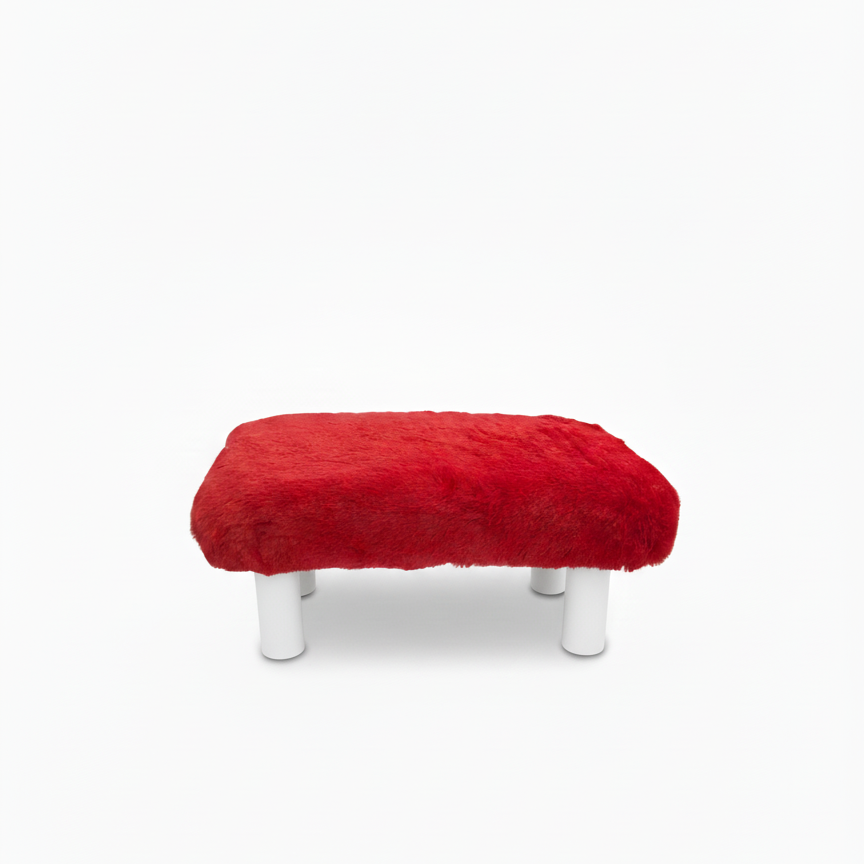 Handcrafted footstool with plush red faux fur top. It has white wooden legs. On a white background. Made by Little Forest Studio.