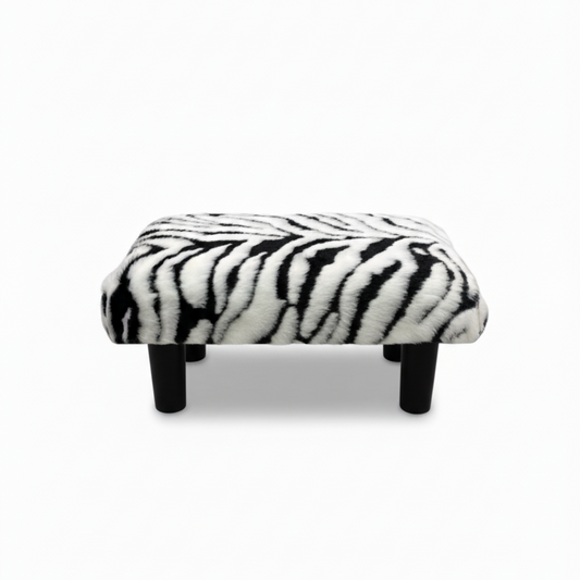 Handcrafted footstool with Zebra print faux fur top and black wood legs. On a white background. Made by Little Forest Studio.